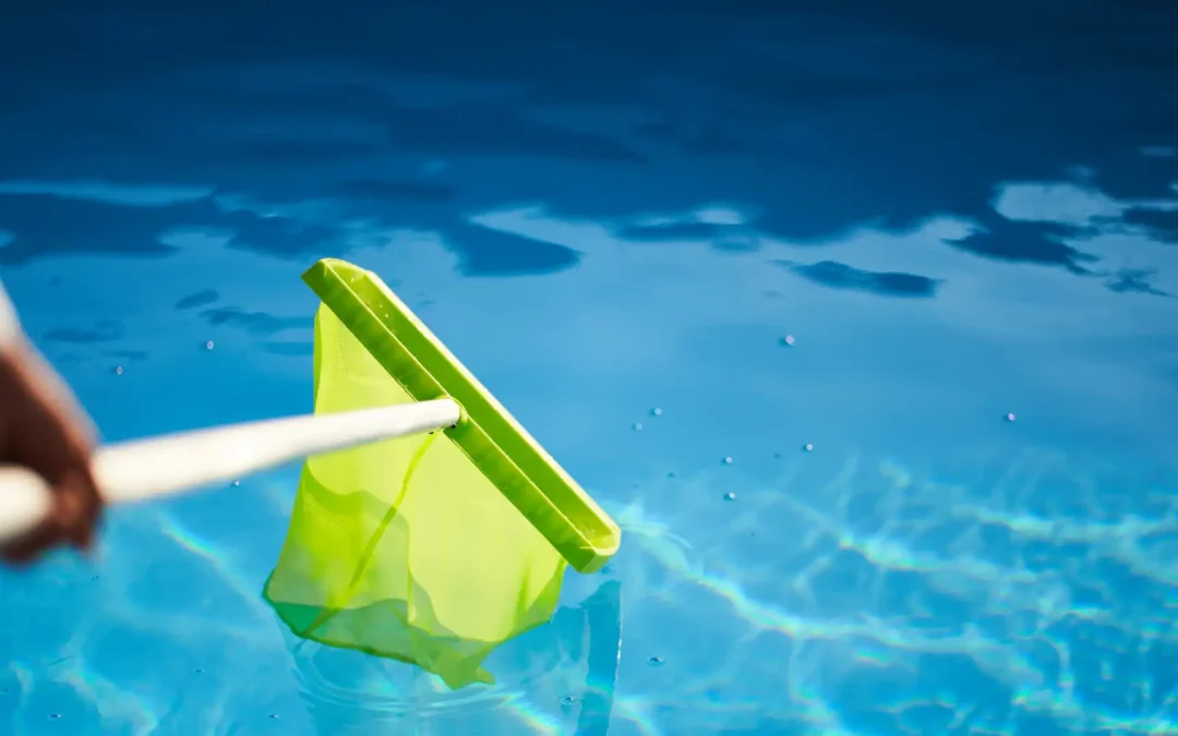 Concrete pool maintenance guide – Someone using a green skimmer to clean a pool